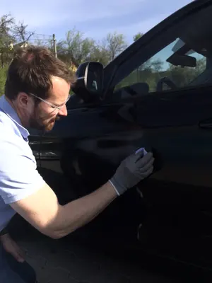 Thomas Gloos arbeitet aufmerksam am Lack eines Fahrzeugs